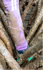 Rosa sinks her arm in the mud to find shells.