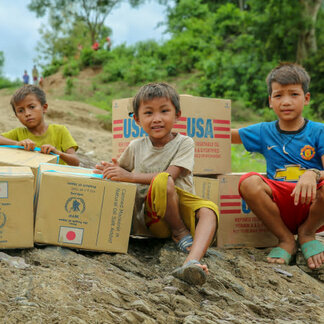 Three boys sitting next to their food ration