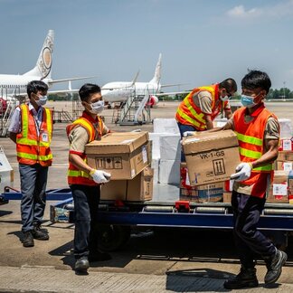 Men offloading boxes of relief supply in an airstrip